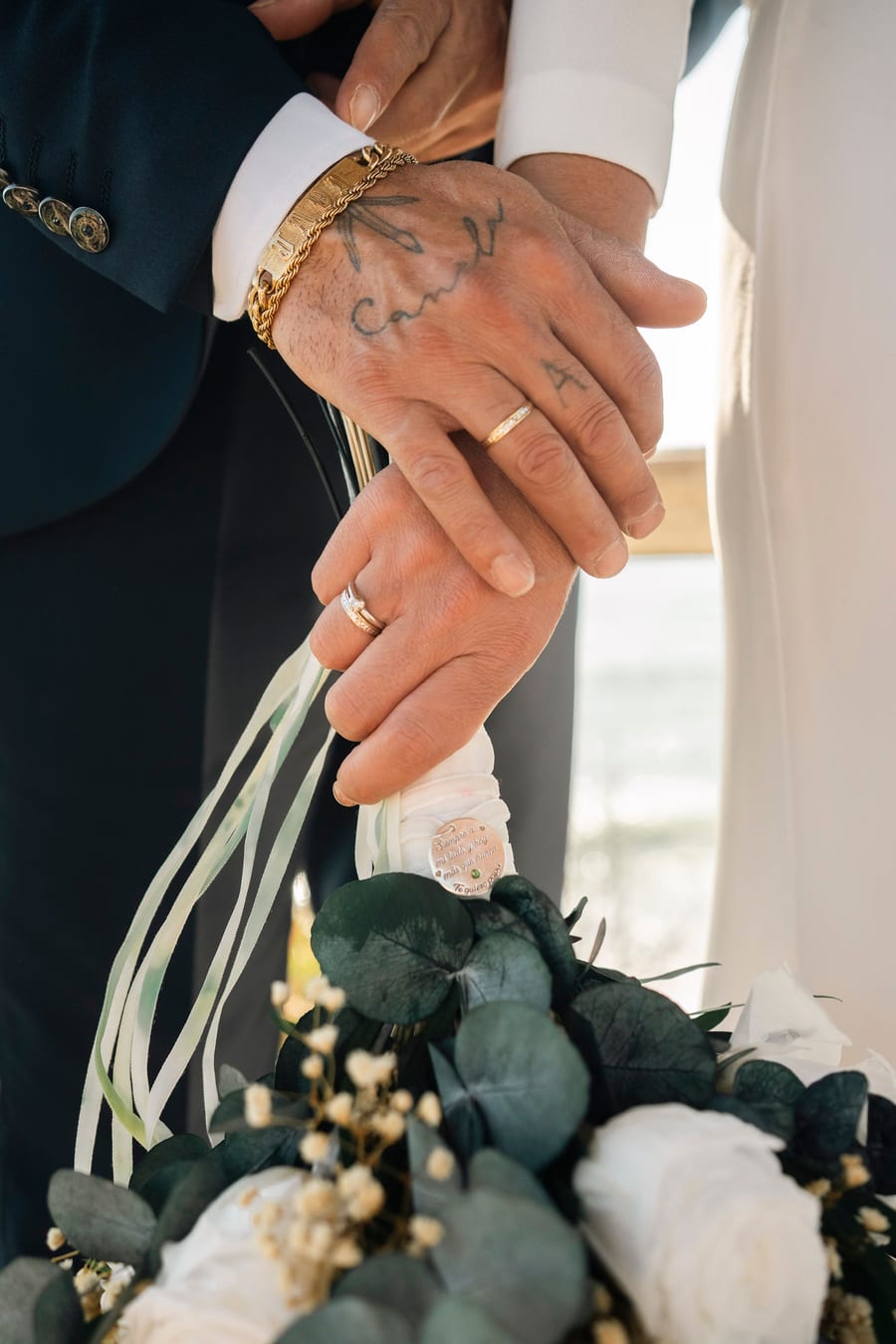 Couple's hands intertwined beside the bridal bouquet