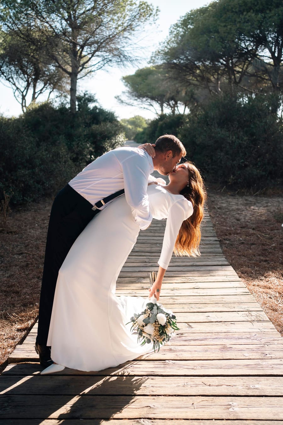 Groom dipping the bride on a wooden path