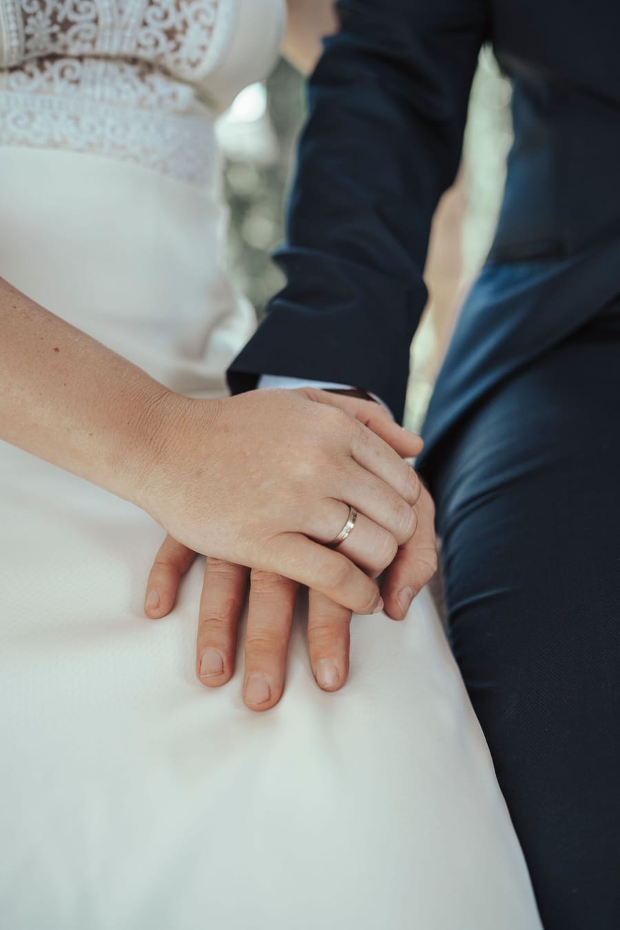 Couple's hands intertwined over the wedding dress