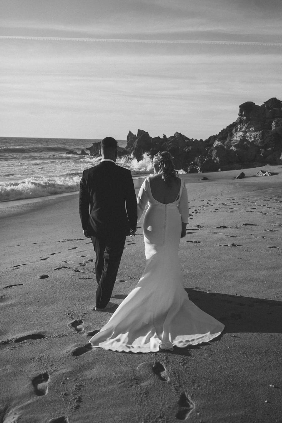 Couple walking away along the beach, in black and white