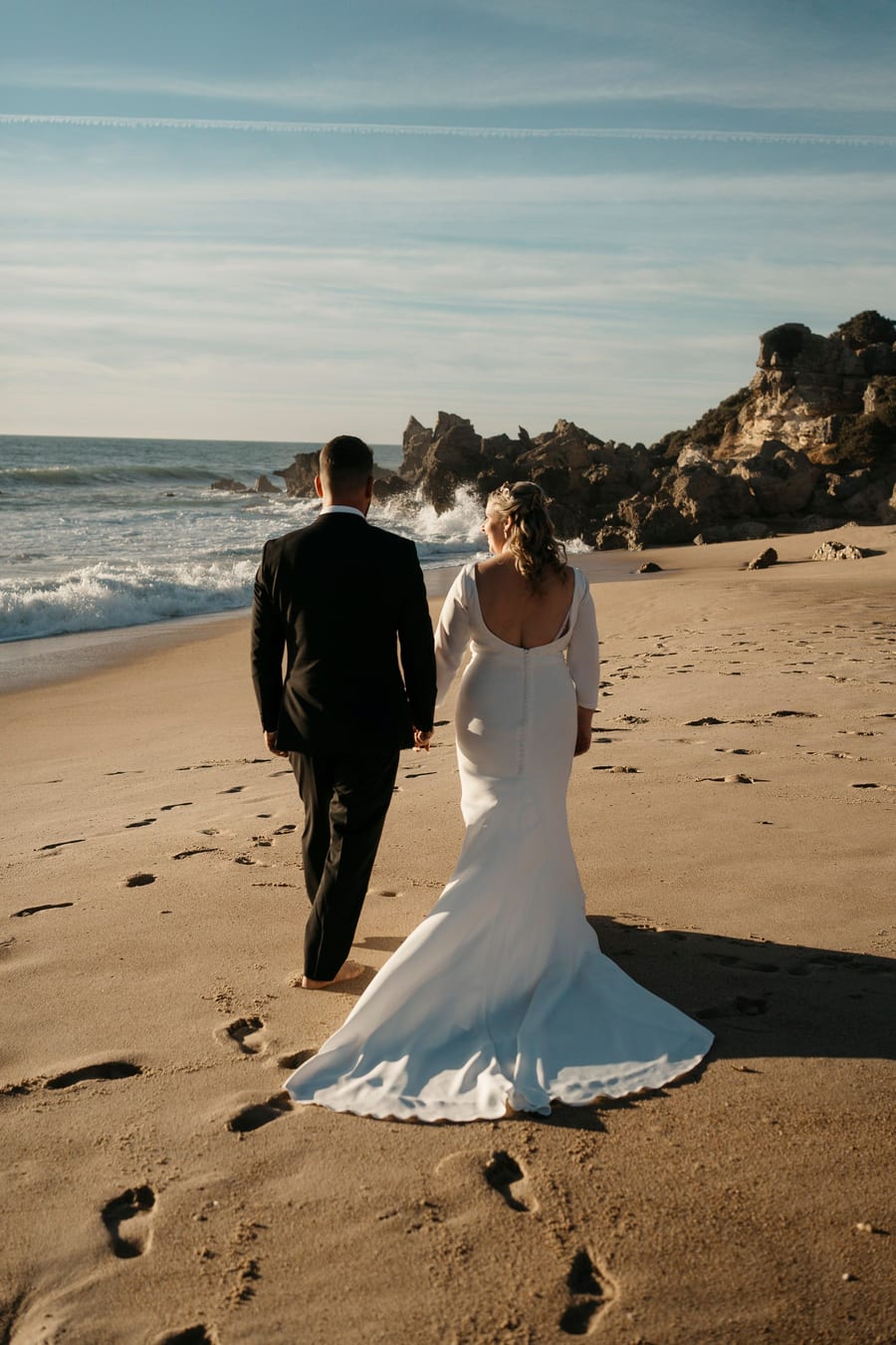 Couple walking barefoot along the shoreline during a post-wedding session