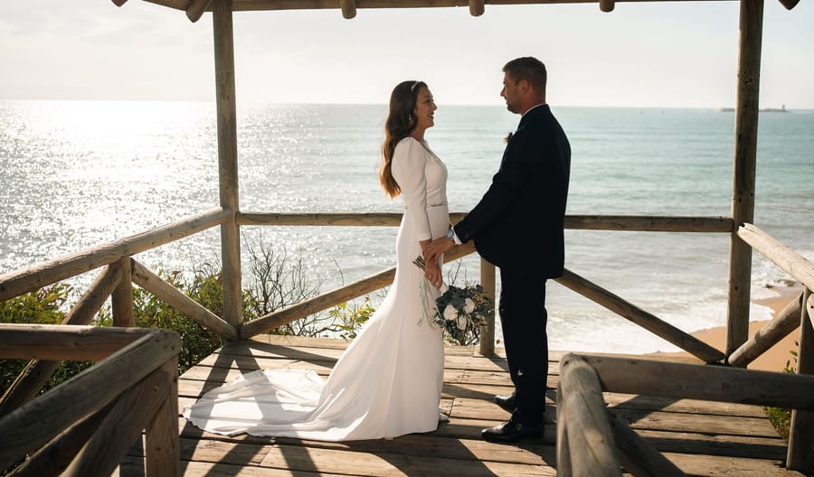 Couple under a wooden pavilion by the sea during a pre-wedding session